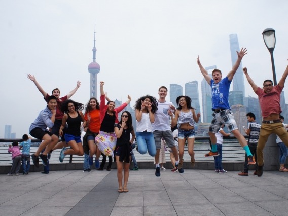 group of students jumping, with Shanghai in the background