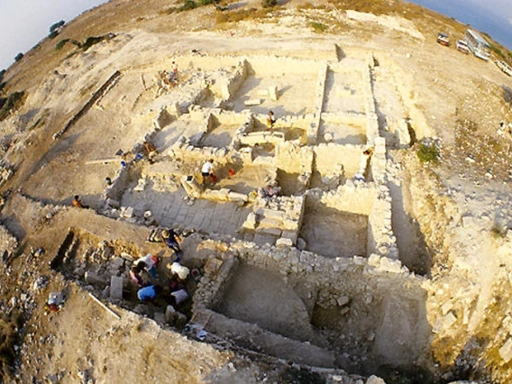 an overhead view of a stone foundation in the ground where archaeologists are excavating ancient remains