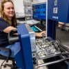 Jessica Barnes sitting in a chair in her lab, loading a sample into an analyzer instrument