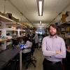 Philip Gutruf stands in his laboratory with researchers working in the background.